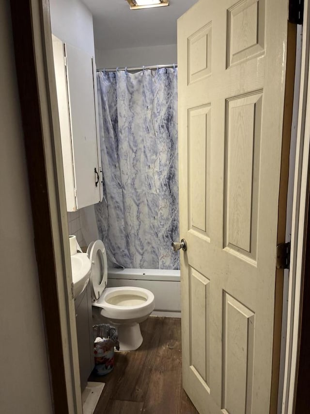 full bathroom featuring hardwood / wood-style floors, vanity, shower / tub combo, and toilet