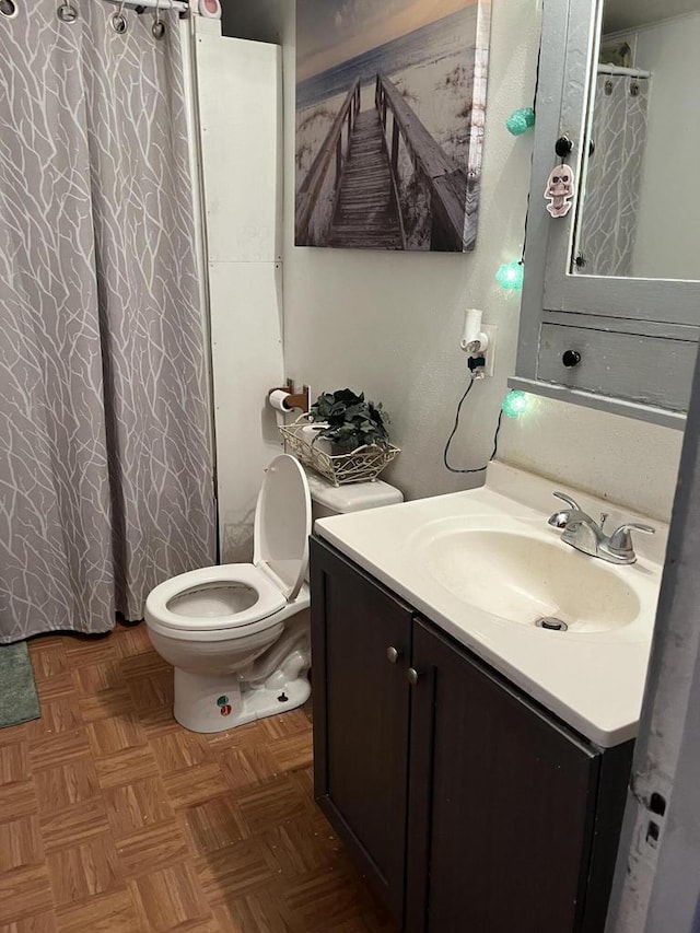 bathroom with vanity, toilet, and parquet floors