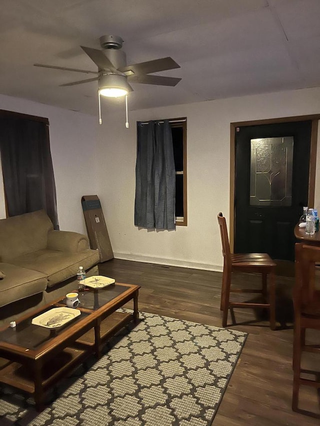 living room featuring ceiling fan and dark wood-type flooring