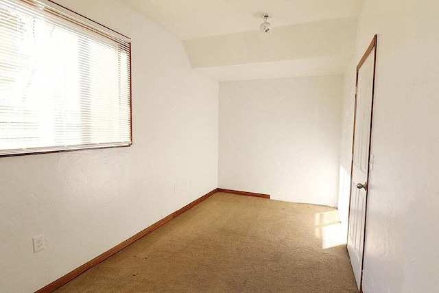 carpeted empty room featuring lofted ceiling