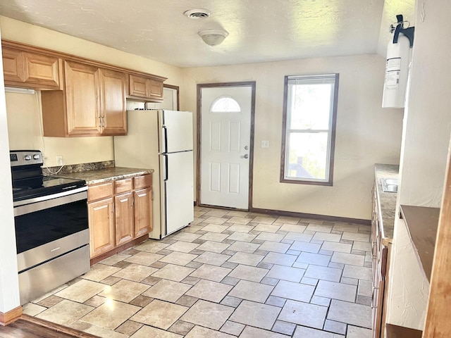 kitchen with a textured ceiling, white refrigerator, stainless steel range with electric stovetop, and sink