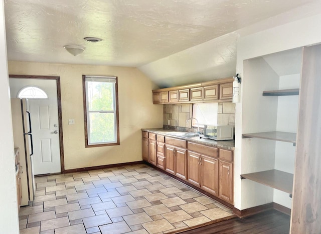 kitchen with fridge, sink, and vaulted ceiling