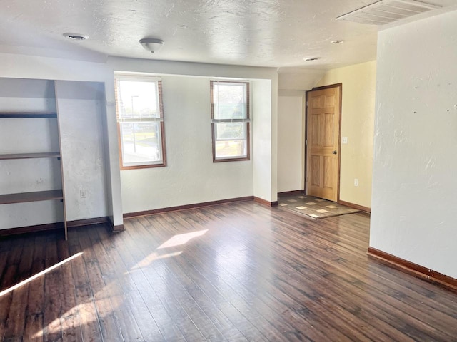 spare room with a textured ceiling and dark wood-type flooring