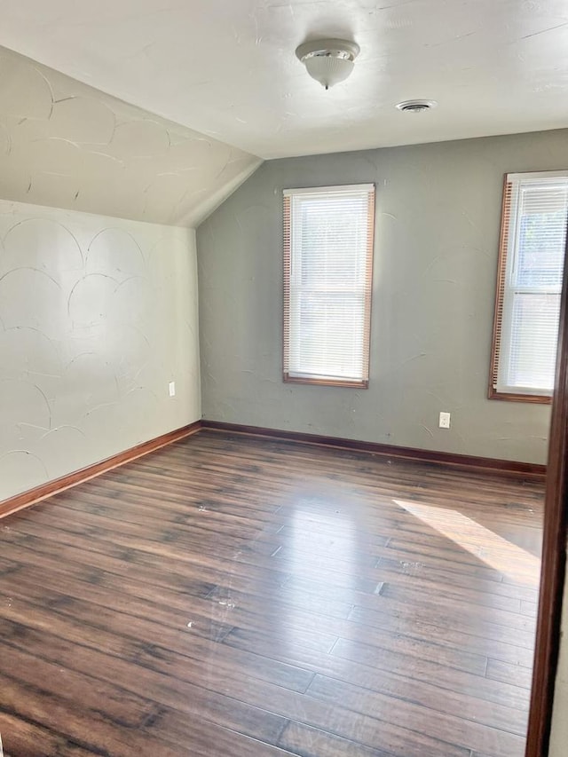 additional living space with a healthy amount of sunlight, dark hardwood / wood-style flooring, and lofted ceiling