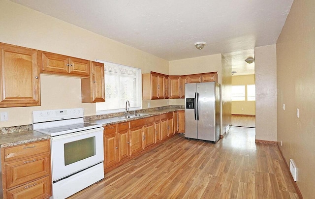 kitchen featuring a healthy amount of sunlight, stainless steel fridge with ice dispenser, white electric range oven, and light hardwood / wood-style floors