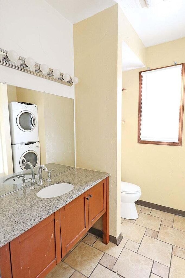 bathroom featuring vanity, toilet, and stacked washer and clothes dryer