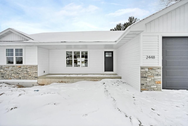 snow covered property entrance featuring a garage