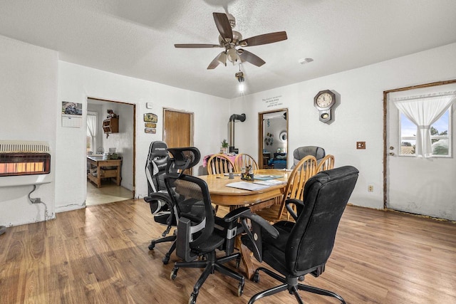 dining area with heating unit, light wood-type flooring, a textured ceiling, and ceiling fan