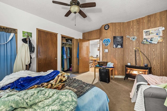 carpeted bedroom featuring a textured ceiling, ceiling fan, and wooden walls