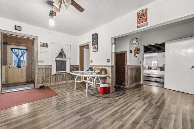 interior space with hardwood / wood-style flooring, a textured ceiling, wood walls, and ceiling fan