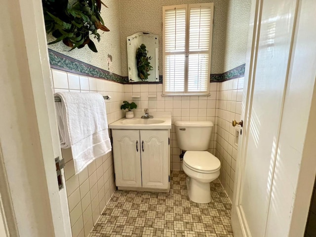 613 College St, Beloit, WI 53511 - half bathroom featuring tile walls, vanity, toilet, and wainscoting