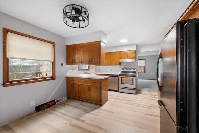 kitchen featuring appliances with stainless steel finishes, light hardwood / wood-style floors, tasteful backsplash, and sink