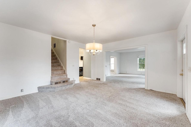 unfurnished living room featuring light colored carpet and an inviting chandelier