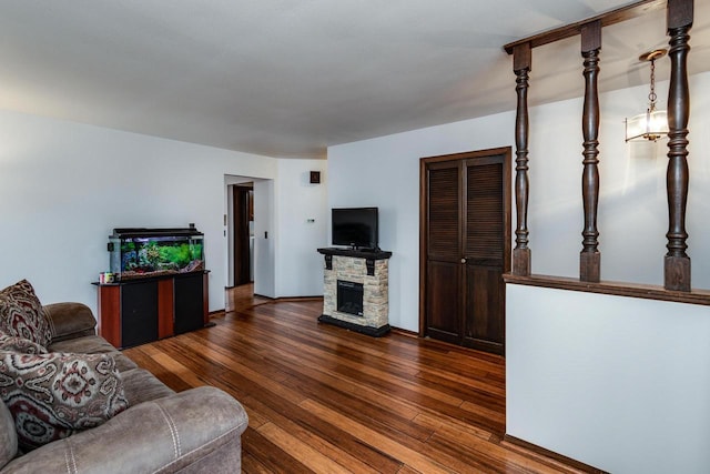 living room featuring a stone fireplace and dark hardwood / wood-style floors