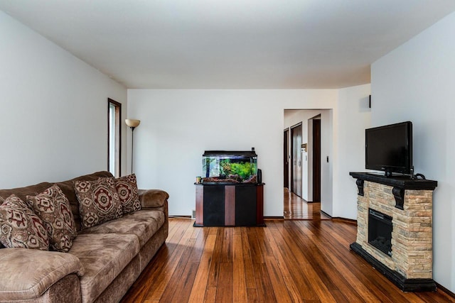 living room with dark hardwood / wood-style floors and a stone fireplace