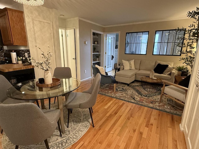 dining area with light hardwood / wood-style flooring and ornamental molding