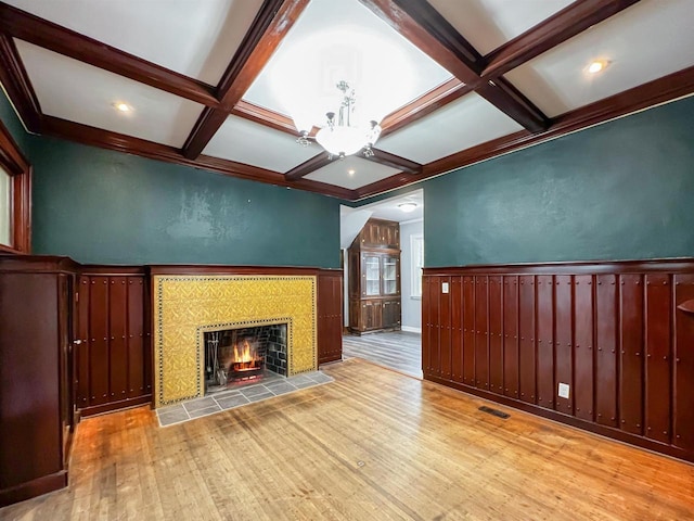 unfurnished living room with beam ceiling, a tile fireplace, and light hardwood / wood-style floors