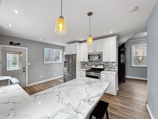 kitchen featuring white cabinets, decorative backsplash, stainless steel appliances, and hanging light fixtures