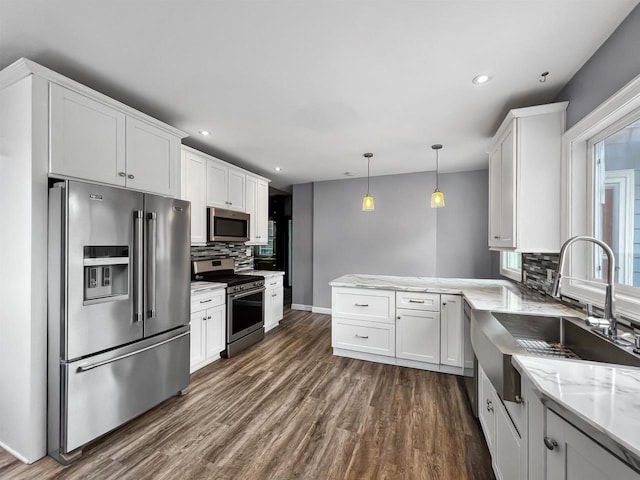 kitchen featuring appliances with stainless steel finishes, dark hardwood / wood-style flooring, sink, pendant lighting, and white cabinetry