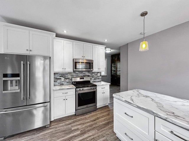 kitchen with white cabinets, pendant lighting, stainless steel appliances, and dark wood-type flooring
