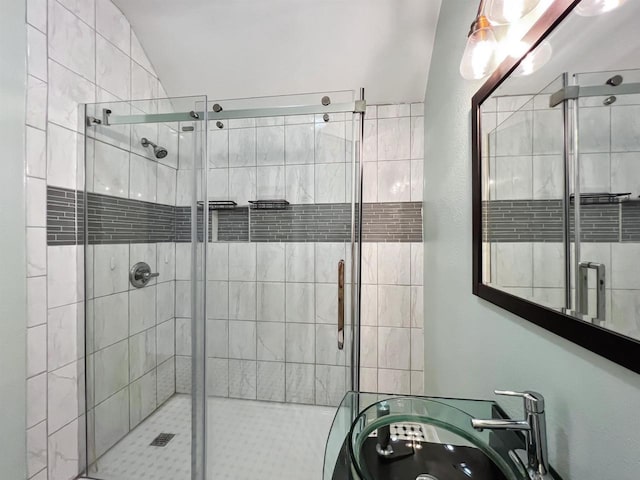 bathroom with lofted ceiling, a shower with shower door, and sink