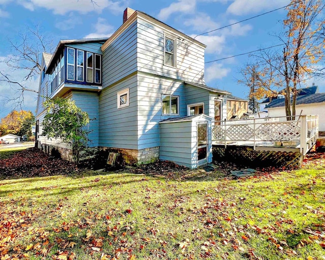 back of house featuring a lawn and a deck
