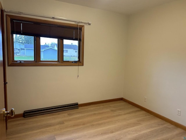 spare room featuring a baseboard radiator and light hardwood / wood-style floors