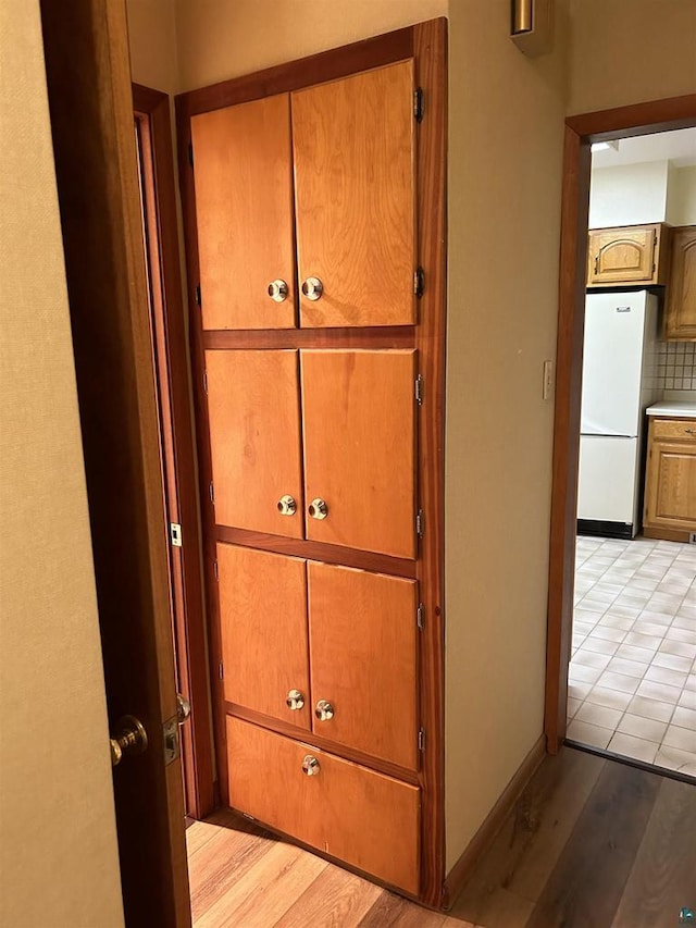 room details with backsplash, white fridge, and light hardwood / wood-style flooring