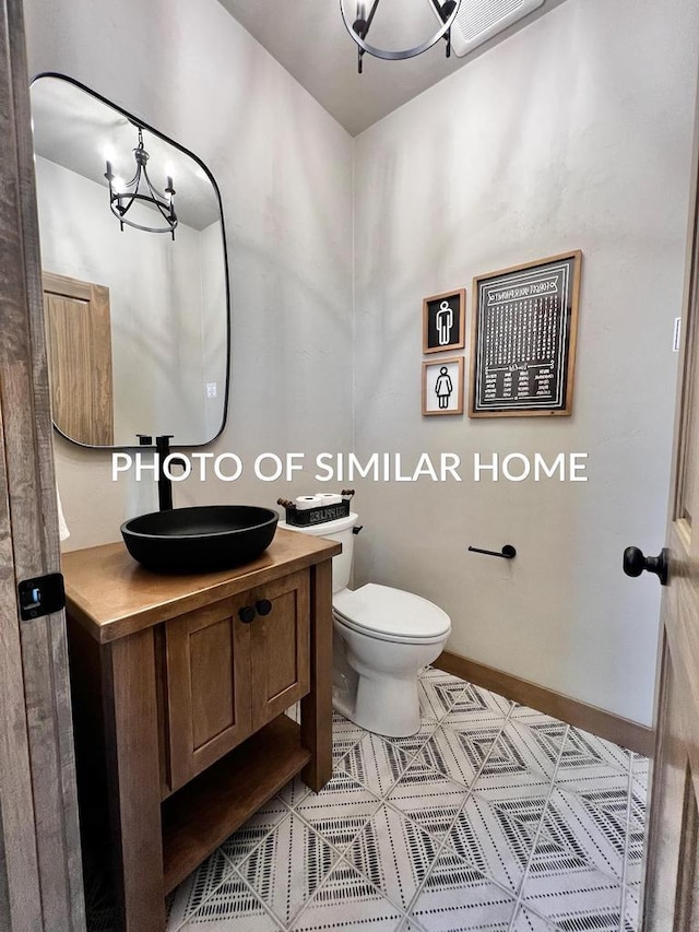 bathroom with baseboards, a notable chandelier, vanity, and toilet