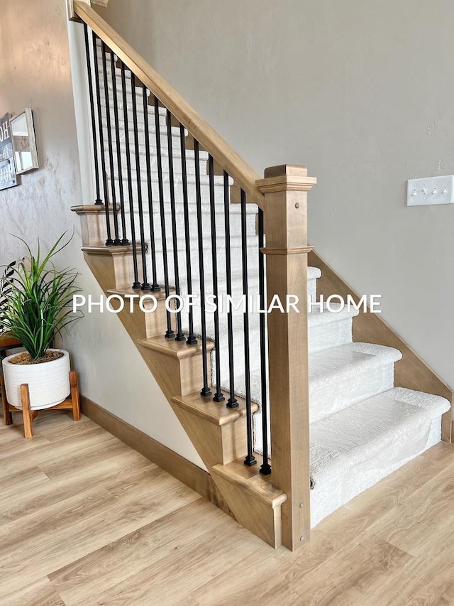 staircase featuring wood finished floors and baseboards