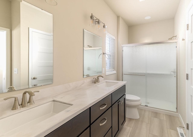 bathroom featuring toilet, a sink, visible vents, and a shower stall