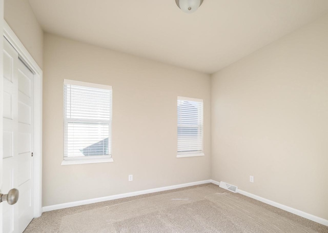 empty room featuring light carpet, a healthy amount of sunlight, baseboards, and visible vents