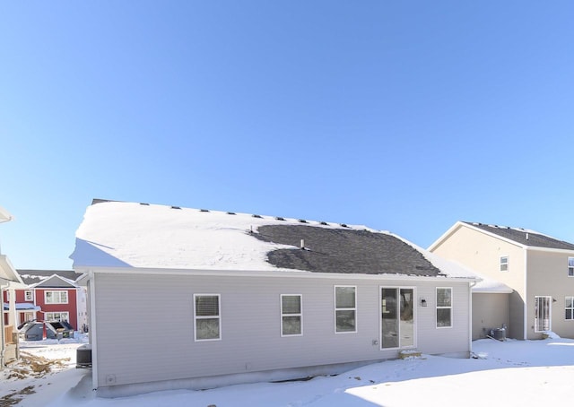 snow covered rear of property featuring central AC