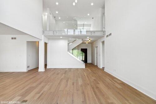 unfurnished living room featuring a high ceiling and light wood-type flooring