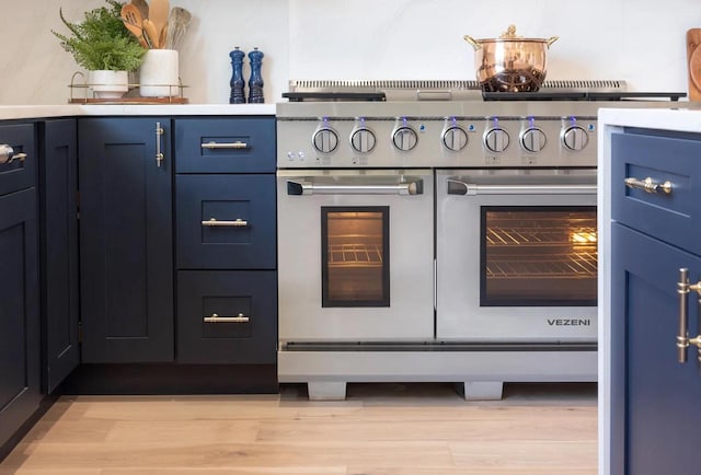 691 Eagleton Dr Unit 55-07, Lake Geneva, WI 53147 - kitchen view of range with two ovens, blue cabinets, light wood-style flooring, and light countertops