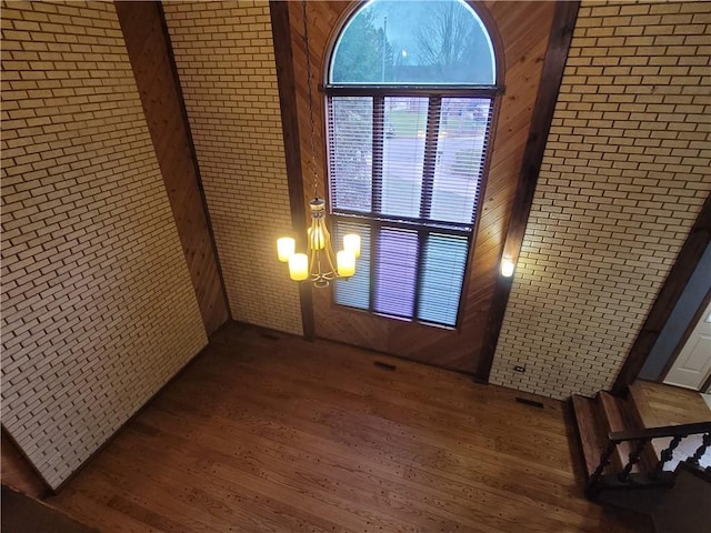 interior space featuring wooden walls, hardwood / wood-style floors, and an inviting chandelier