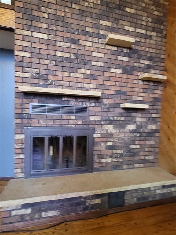 room details featuring wood-type flooring, a fireplace, and wooden walls