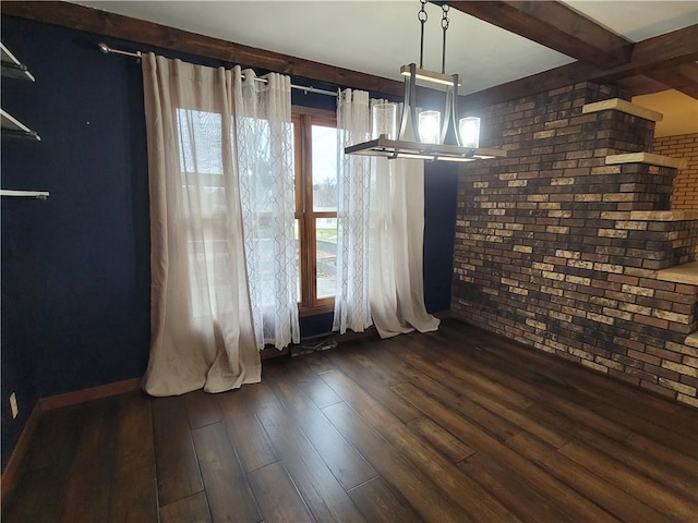 unfurnished dining area with dark hardwood / wood-style floors and brick wall