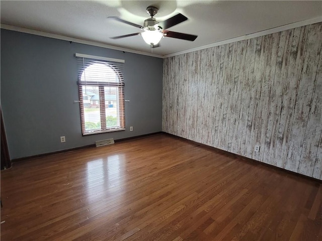 empty room with ceiling fan, dark hardwood / wood-style flooring, and ornamental molding