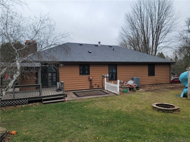 back of property with a fire pit, central AC unit, a deck, and a yard