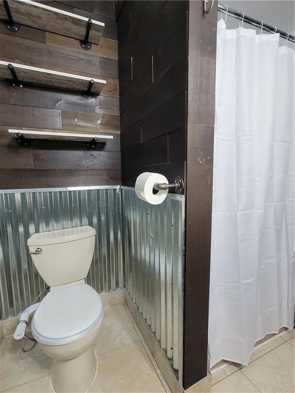 bathroom featuring tile patterned flooring, toilet, and wooden walls