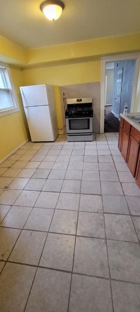 kitchen featuring light tile patterned floors, gas stove, and white refrigerator