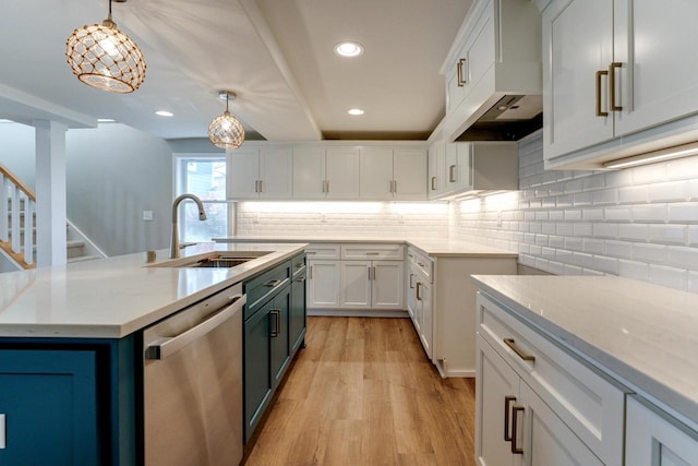 kitchen with stainless steel dishwasher, sink, pendant lighting, light hardwood / wood-style flooring, and white cabinetry