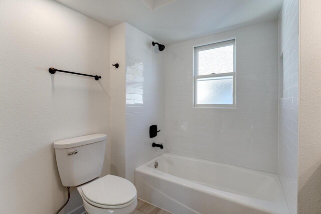 bathroom featuring hardwood / wood-style floors, toilet, and tiled shower / bath