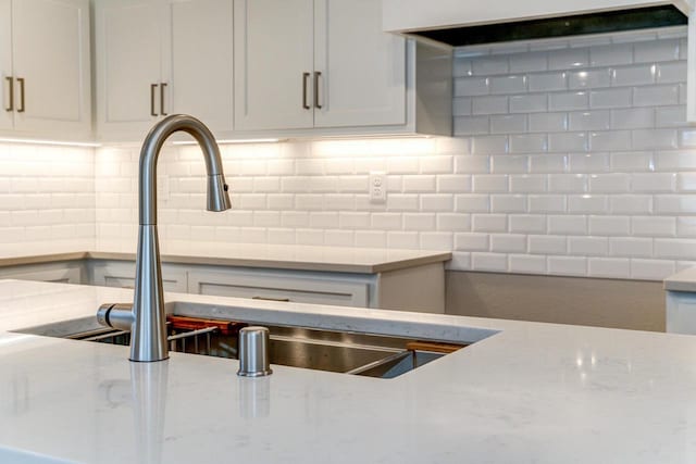 kitchen featuring decorative backsplash, light stone countertops, and sink