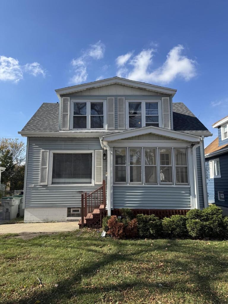 view of front of house featuring a sunroom and a front yard