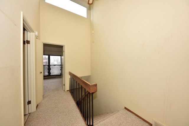 hallway featuring light carpet and a towering ceiling