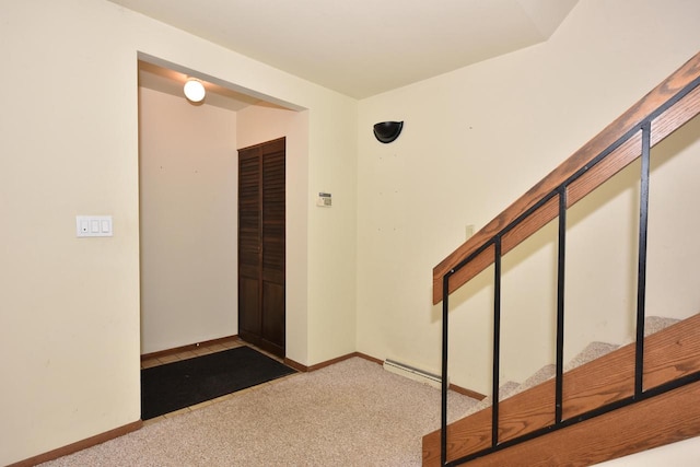 foyer entrance featuring baseboard heating and carpet