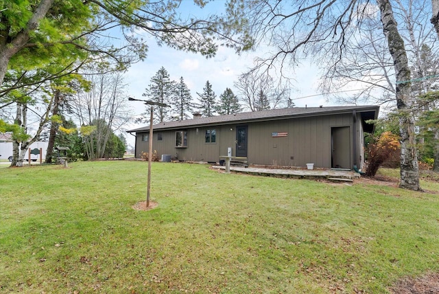 back of property featuring central air condition unit and a yard