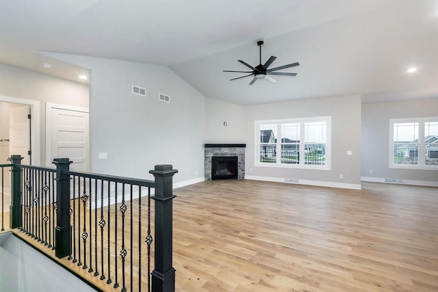 living room with ceiling fan, light wood-type flooring, lofted ceiling, and a fireplace